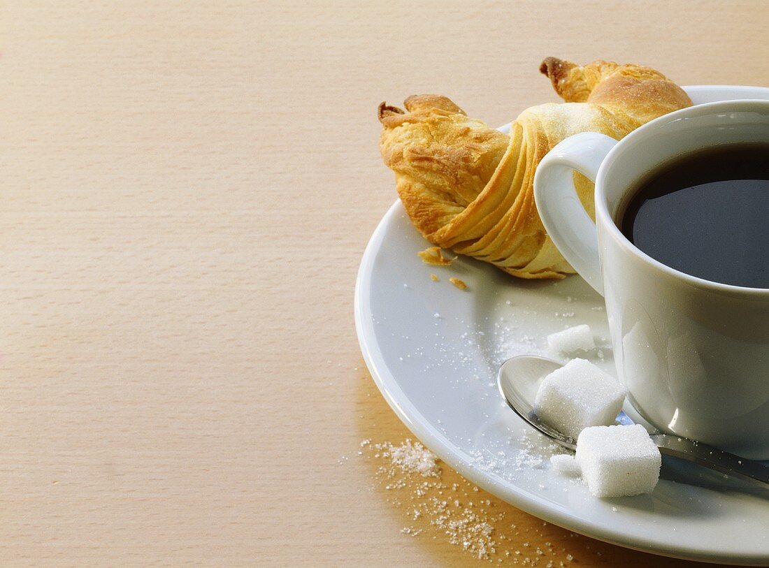 A cup of coffee with croissant