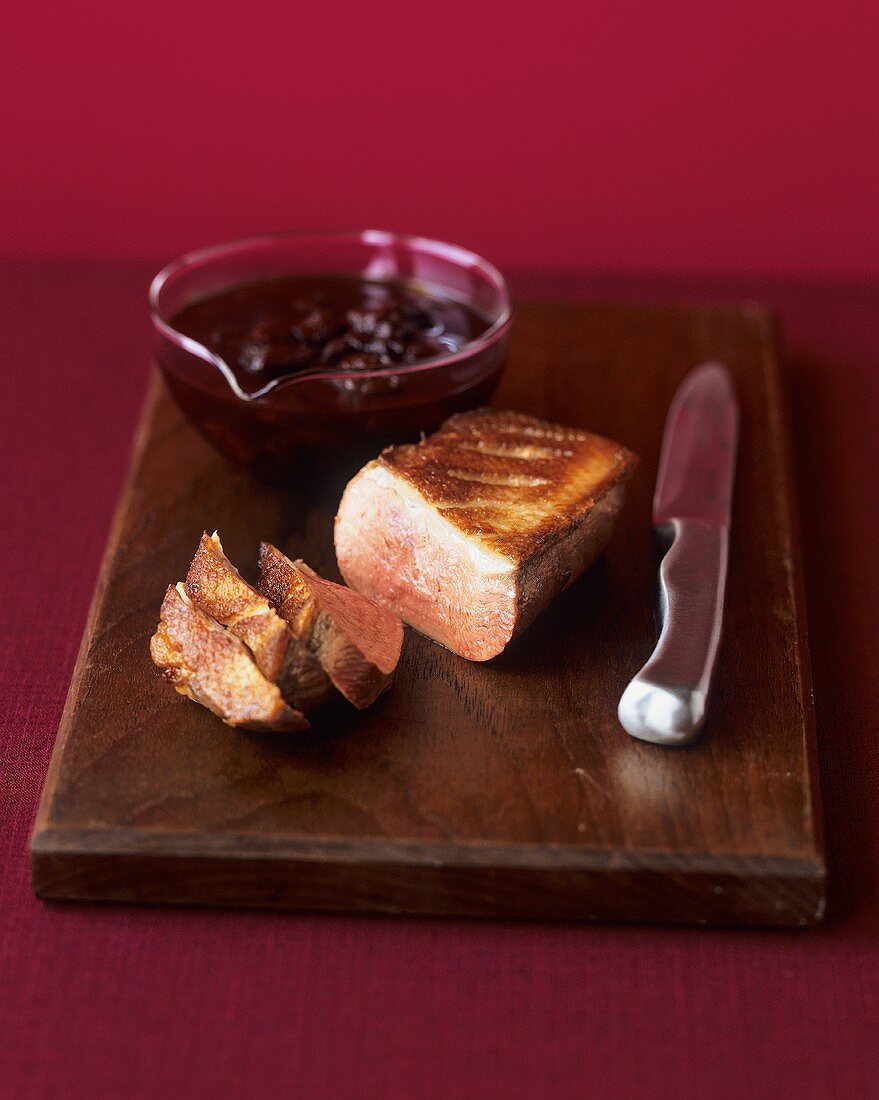 Duck breast with cherry sauce on wooden board