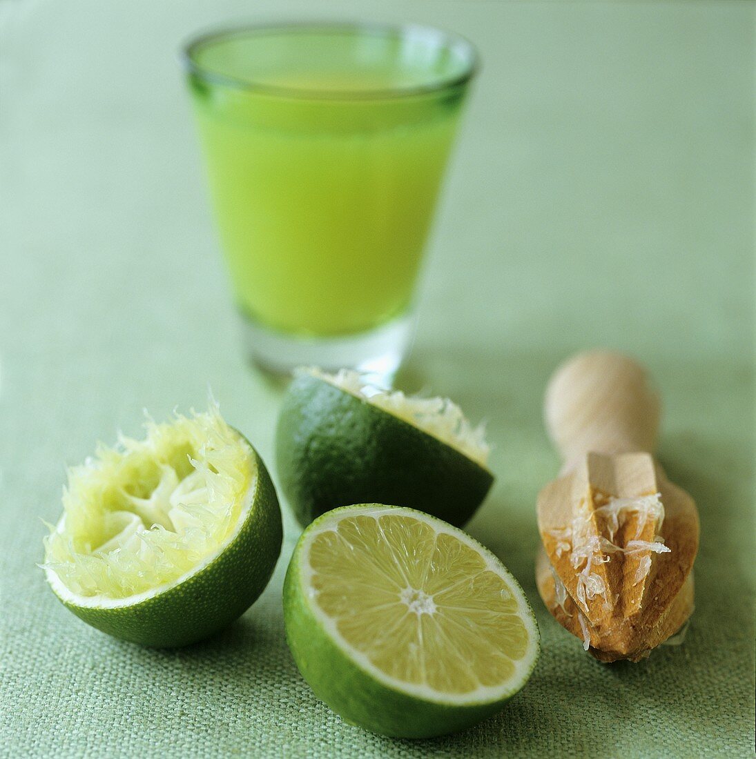 Lime halves, wooden citrus squeezer and lime juice