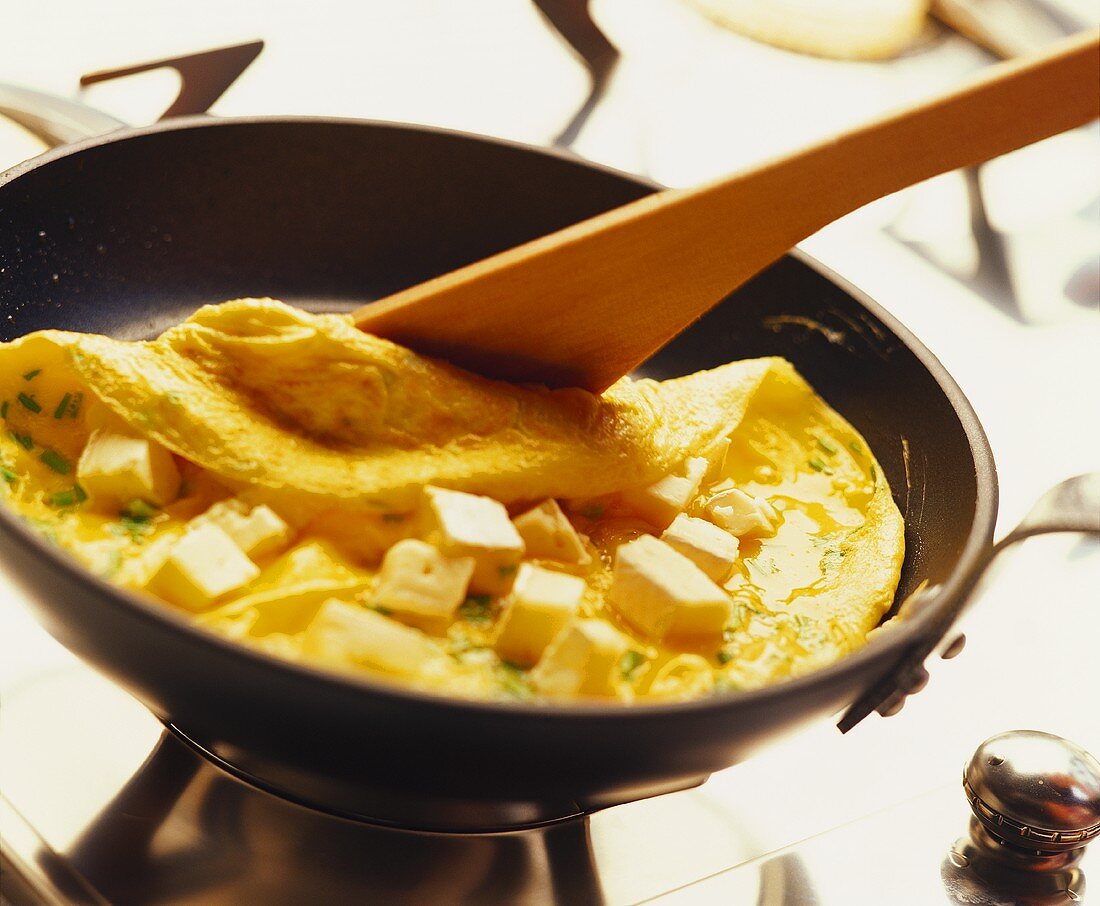 An omelette being folded in a frying pan