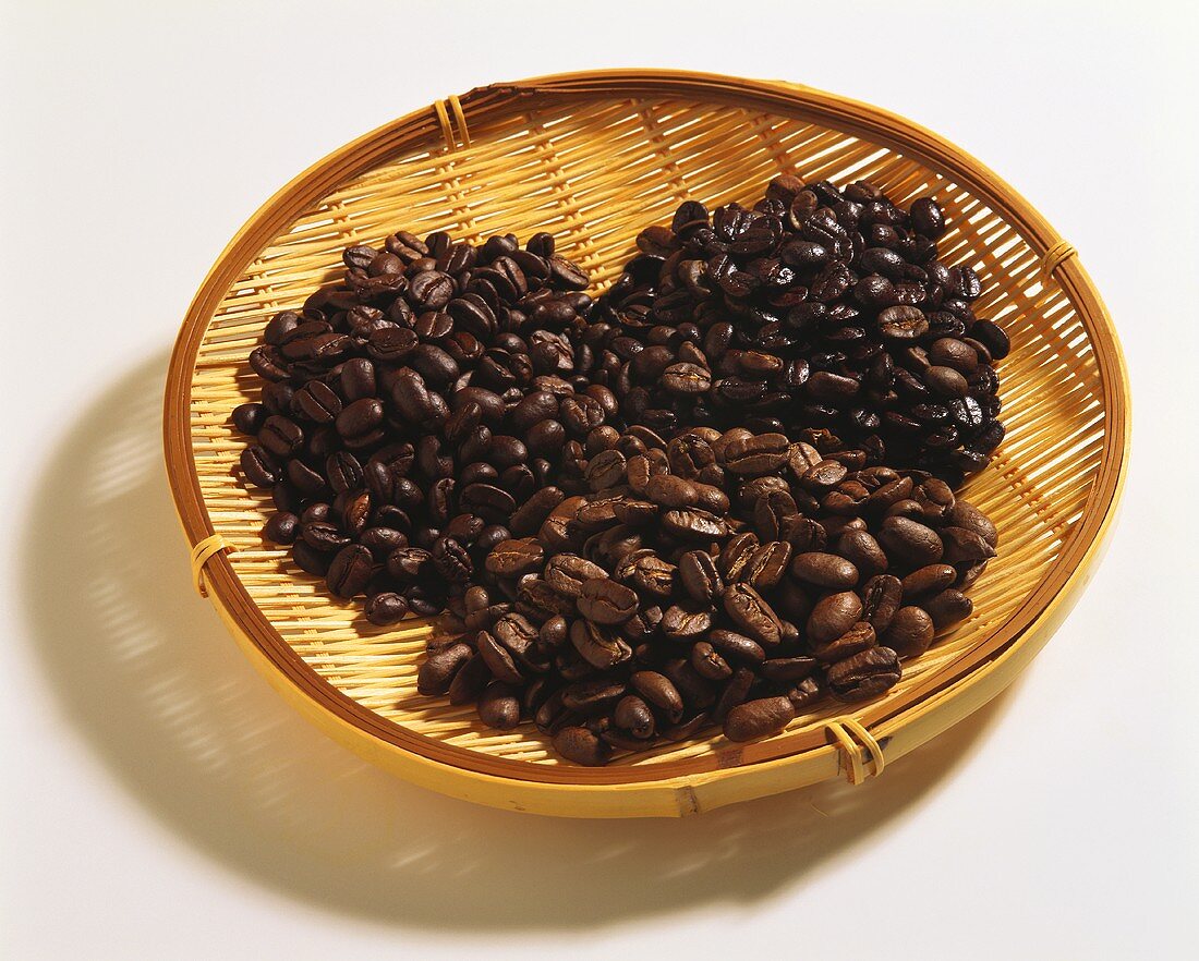 Three types of coffee beans on wicker tray