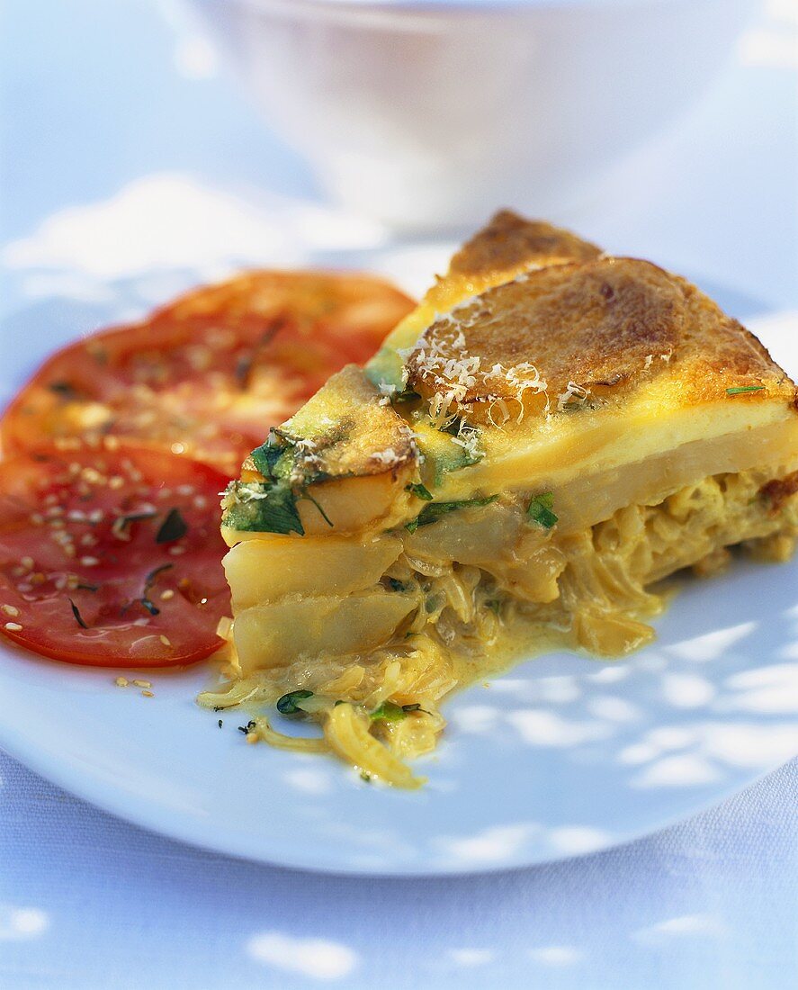 Ein Stück Kartoffel-Zwiebel-Tortilla mit Tomatenscheiben