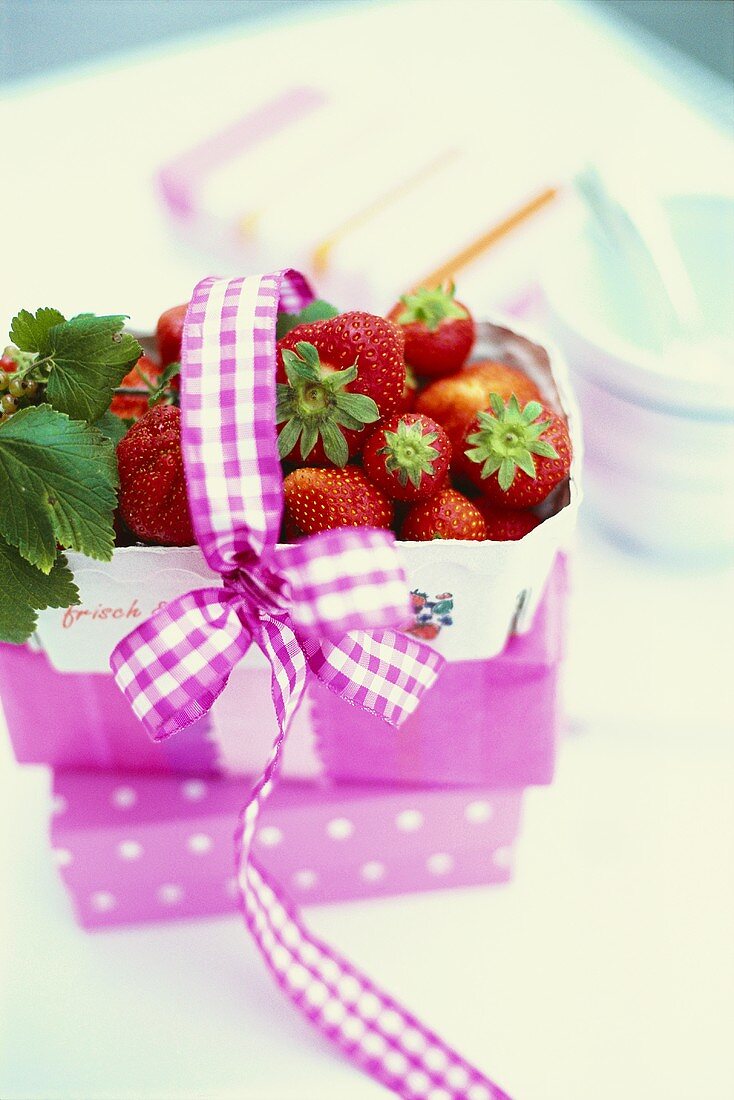 Lila Körbchen mit frischen Erdbeeren und Schleife