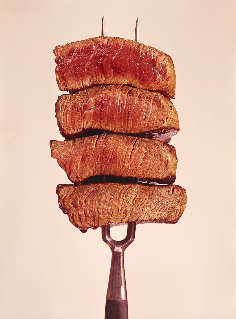 Four steaks with different degrees of cooking on meat fork