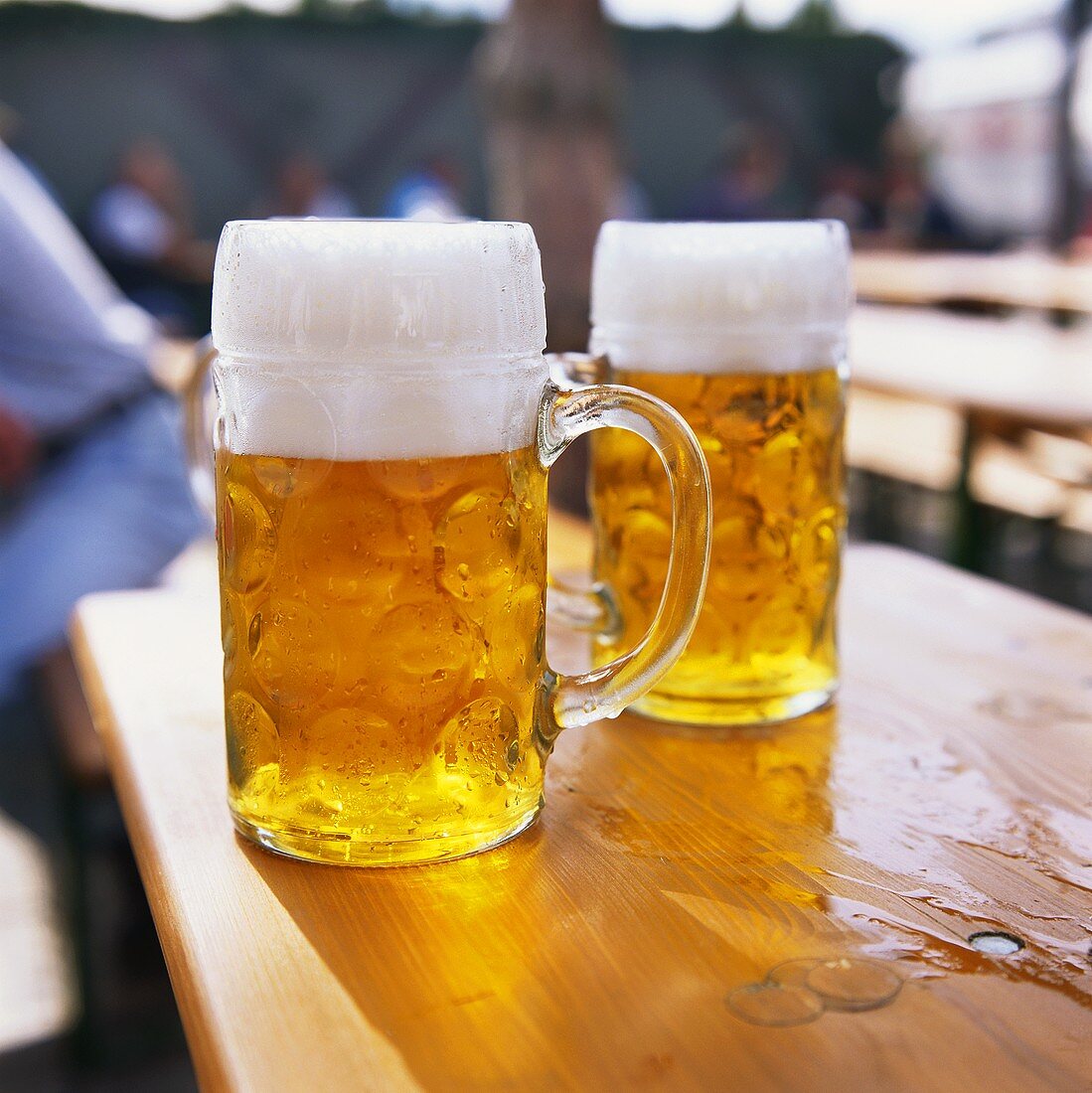 Two tankards of cold beer on a wooden table
