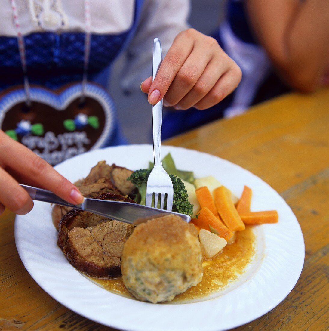 Woman eating veal shank with bread dumpling