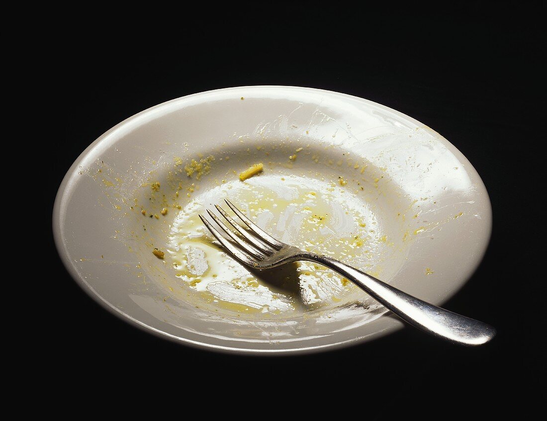 An empty plate with scraps of pesto