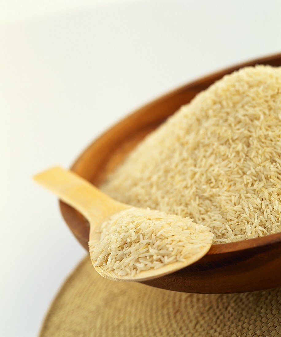 Fragrant rice in wooden bowl and on wooden spoon