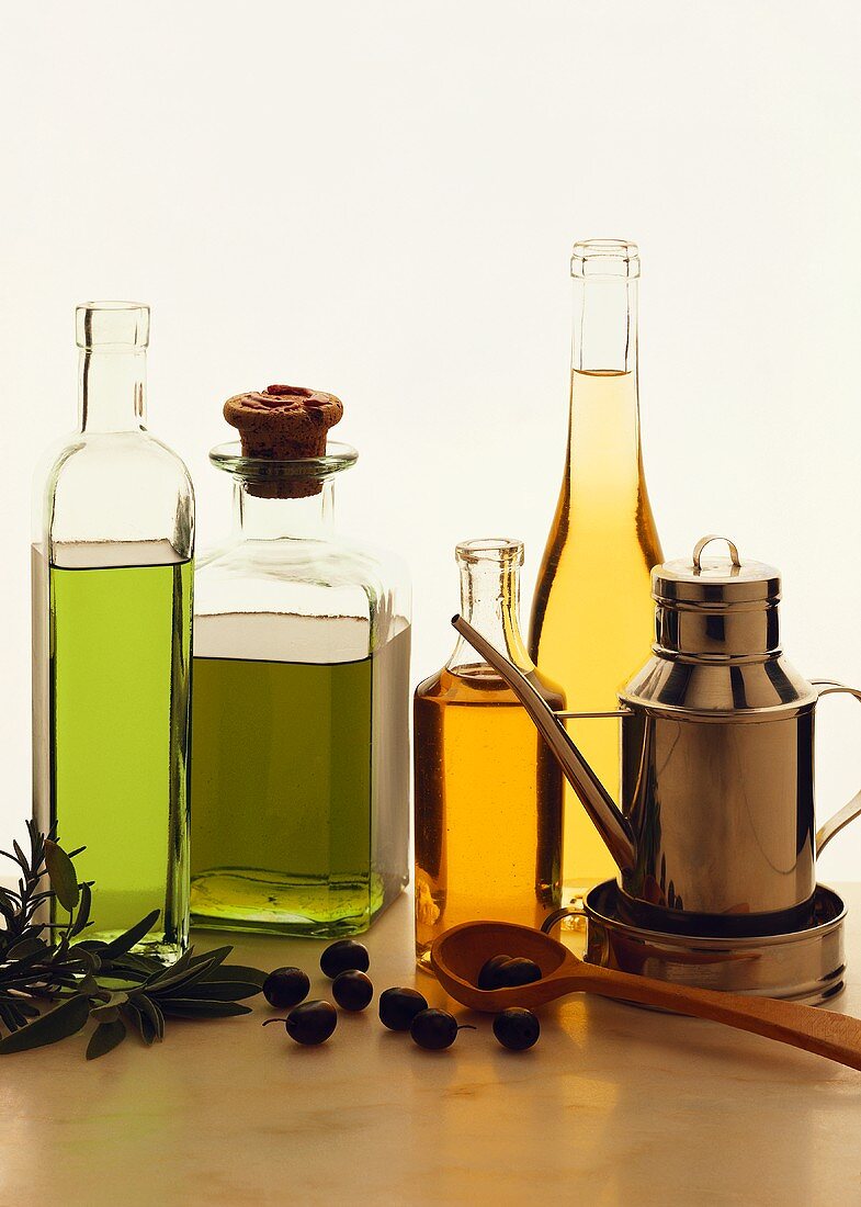 Various types of olive oil in bottles; olive branch; olives
