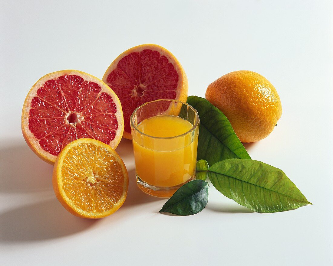 Orangensaft, frische Orangen, rosa Grapefruit und Blätter