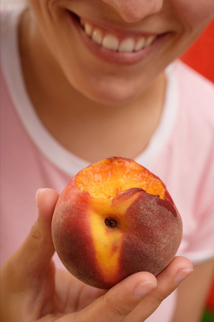 Woman holding a peach with a bite taken