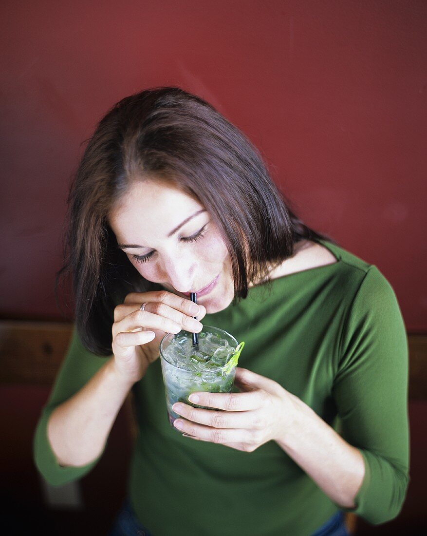 Junge Frau trinkt Mojito mit Strohhalm