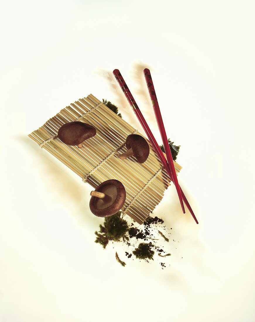 Still life with shiitake mushrooms, bamboo mat & chopsticks