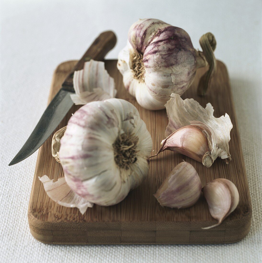 Garlic with knife on wooden board
