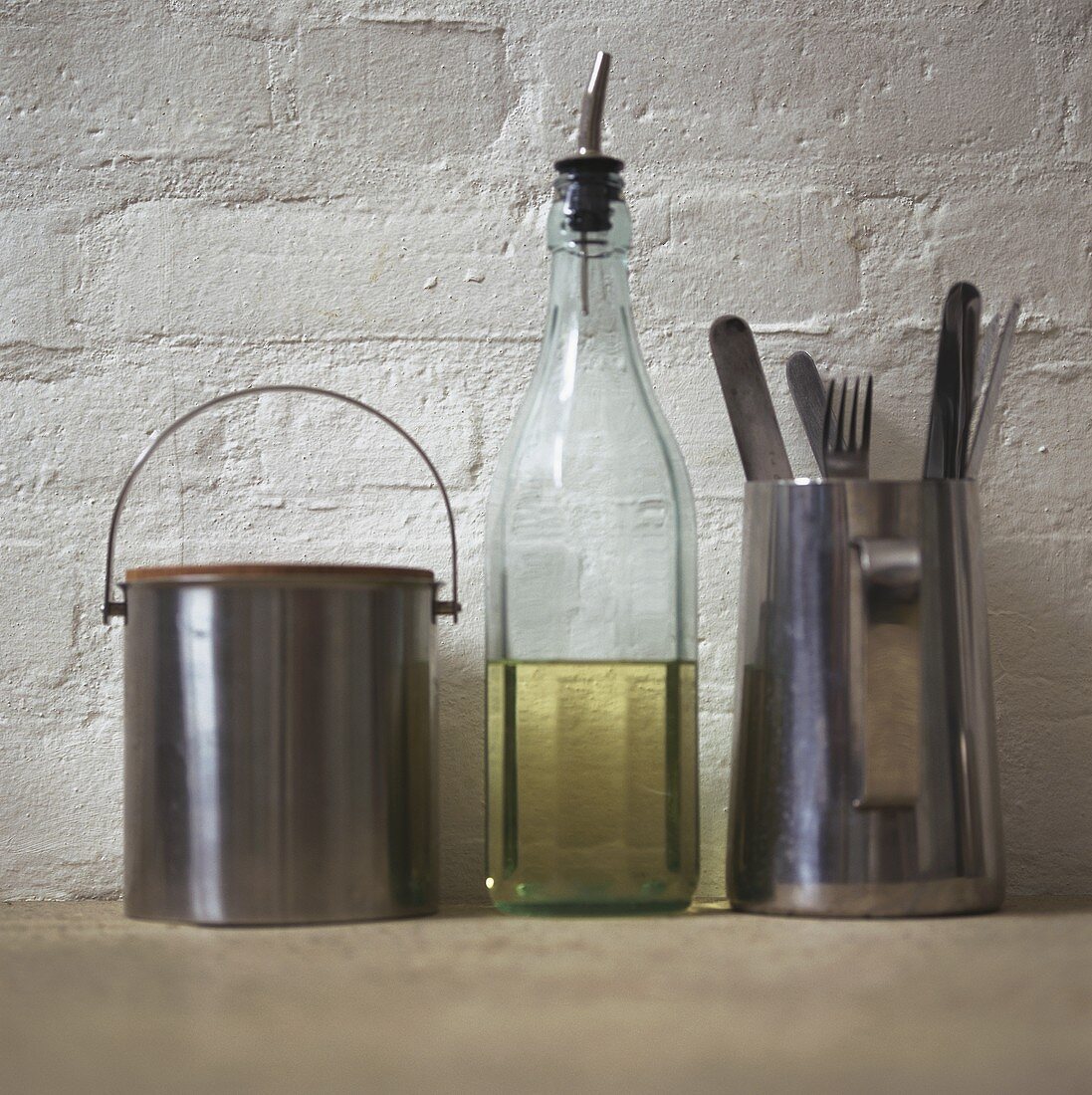 Kitchen shelf with small bucket, oil bottle and cutlery