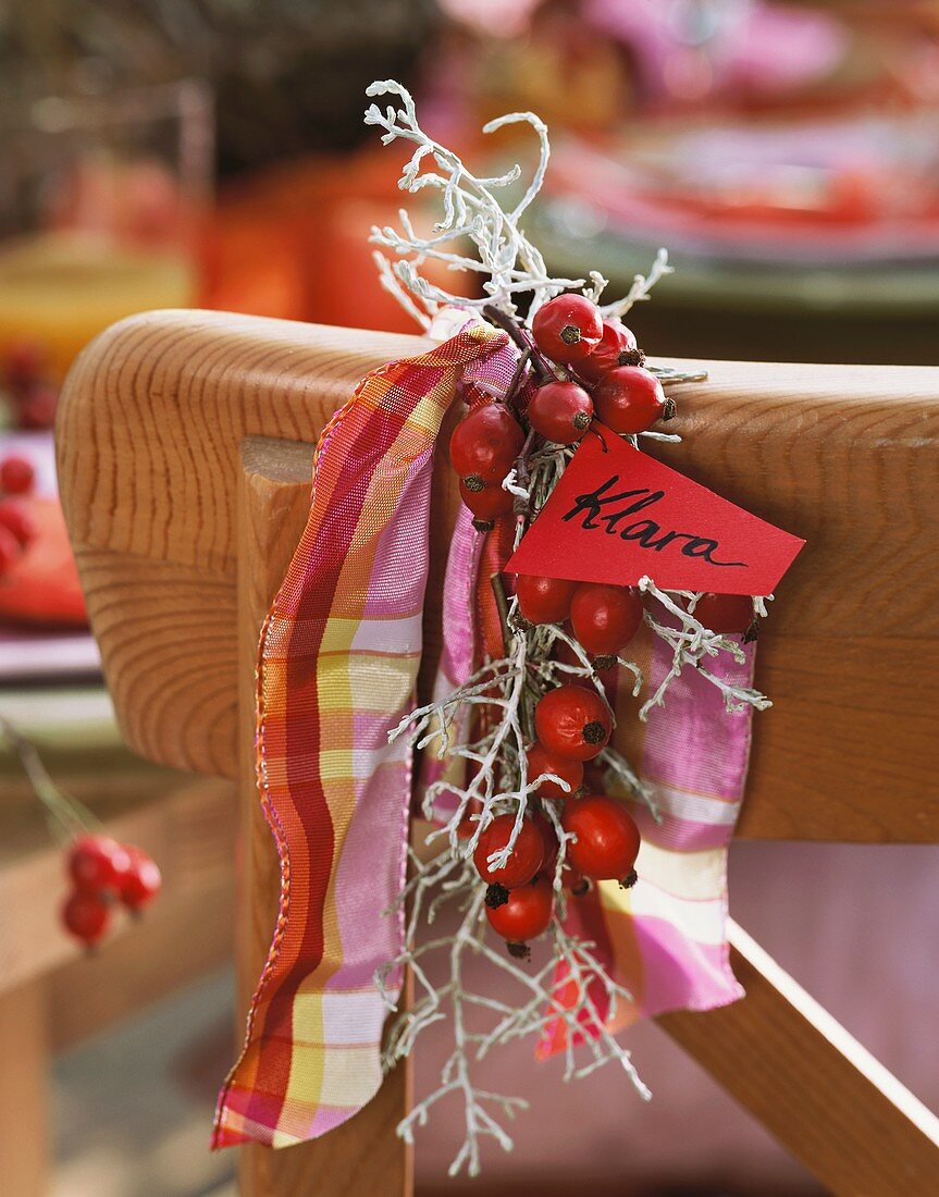 Rose hip decoration with place card on chair back