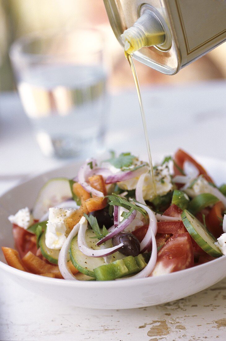 Drizzling Greek salad with olive oil