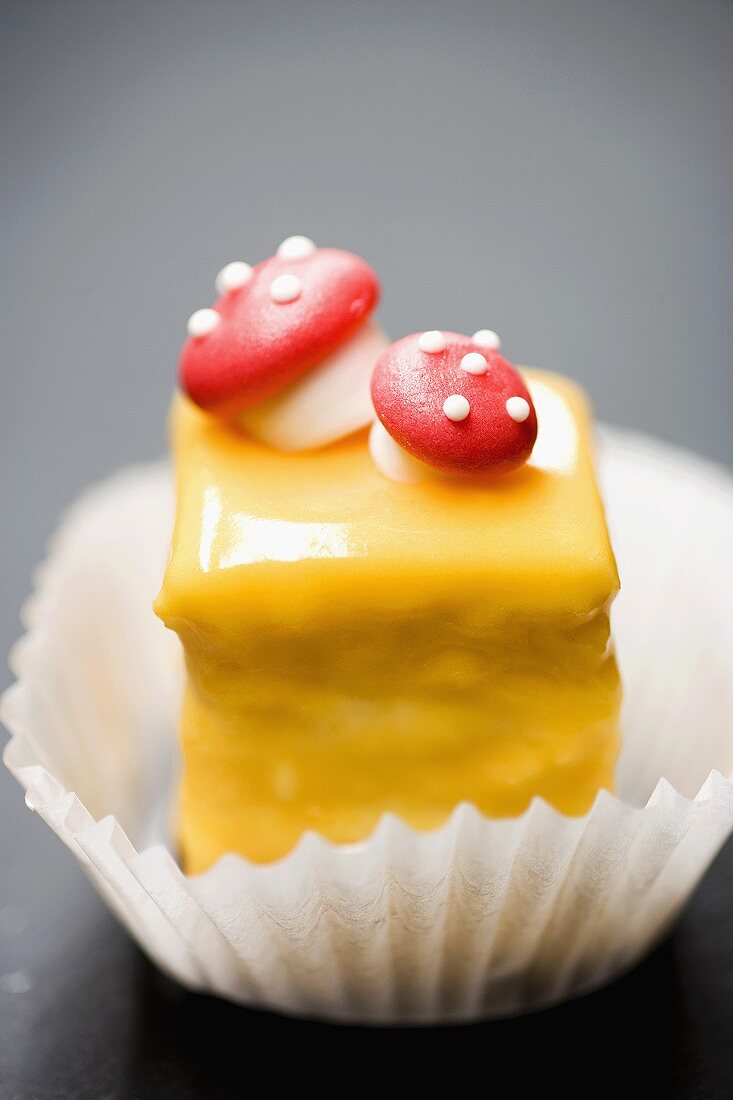 Petit four with yellow glacé icing and fly agarics
