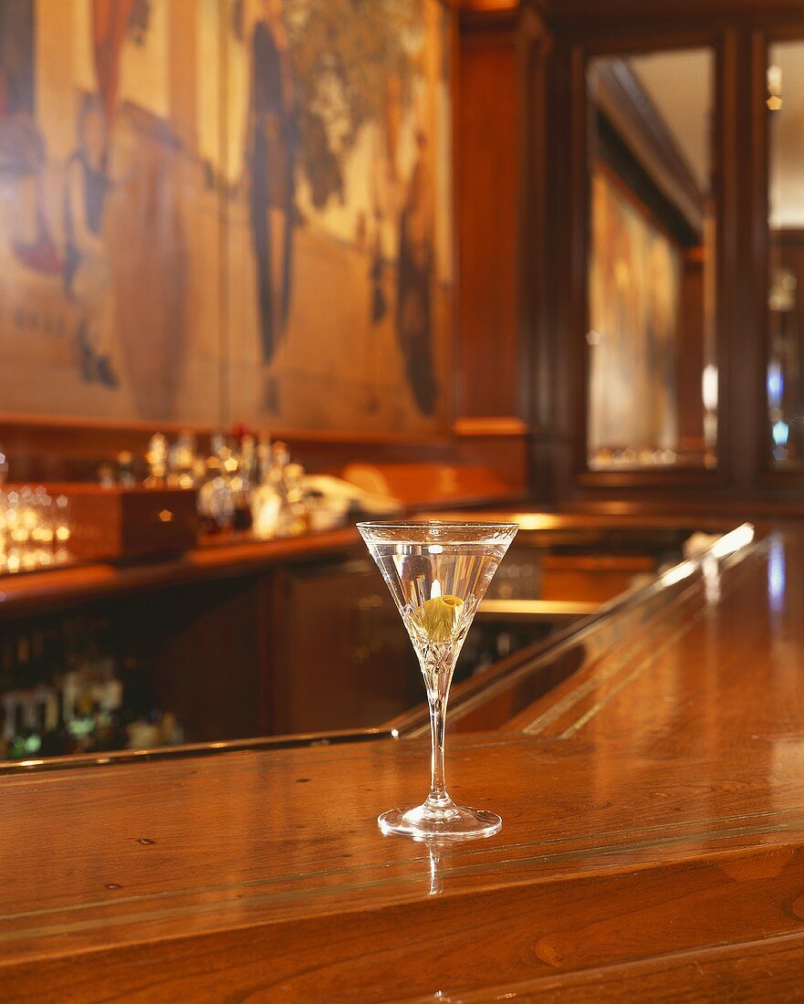 A glass of Martini with olive in a bar