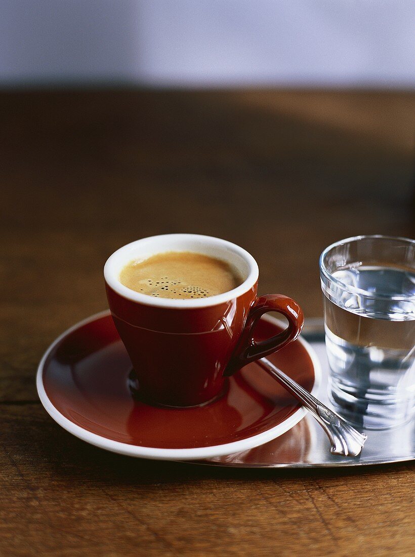 Eine Tasse Espresso und ein Glas Wasser