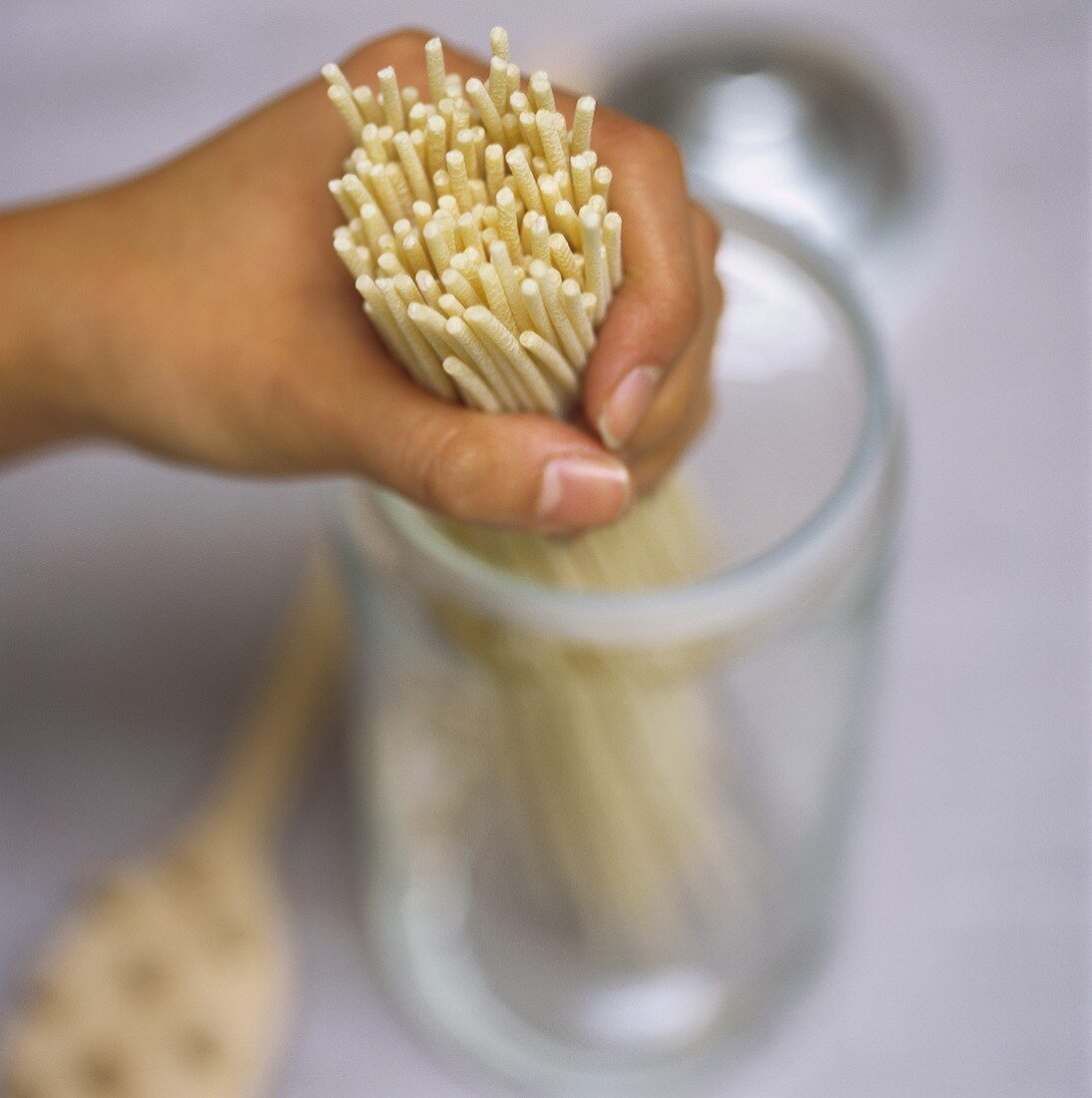 Hands putting pasta into a storage jar