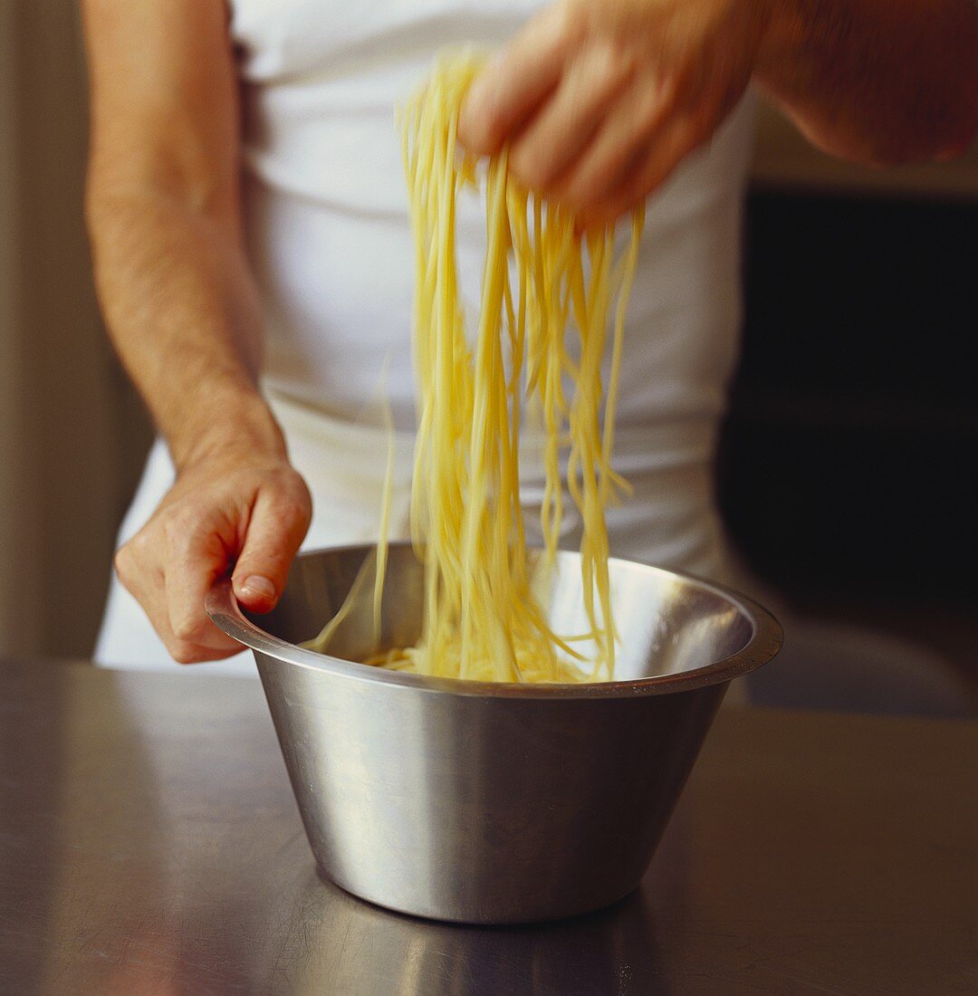 Hand hebt gekochte Spaghetti aus dem Topf