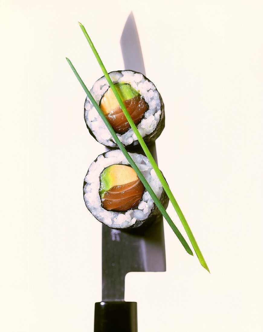 Two maki sushi with salmon and avocado on knife