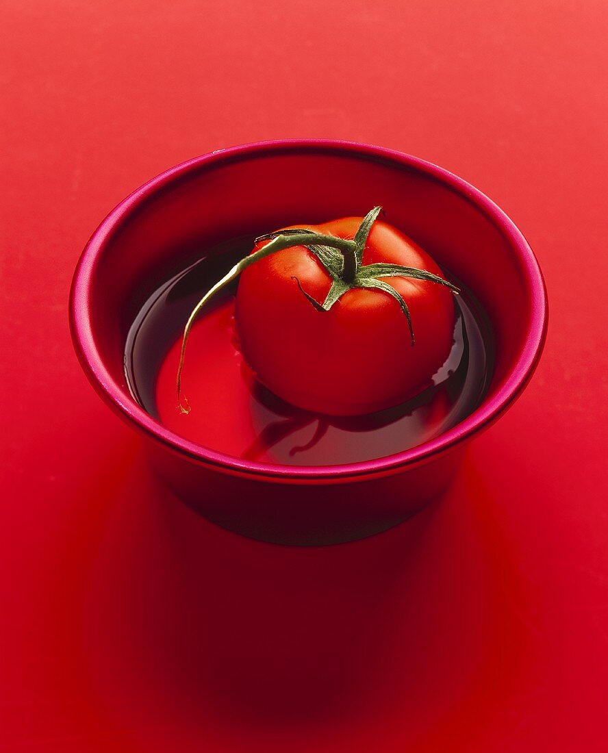 A tomato in a small bowl of water