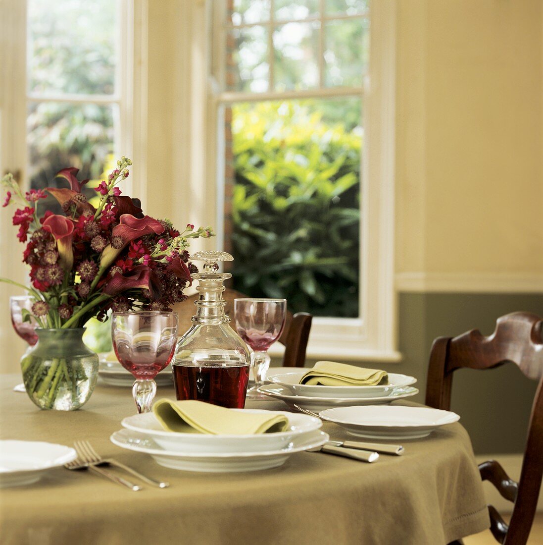 Festlich gedeckter Tisch mit Blumenstrauss und Rotwein