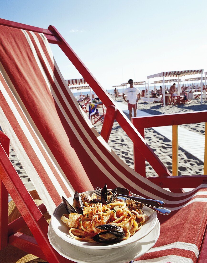 Linguine mit Meeresfrüchten auf Liegestuhl am Strand