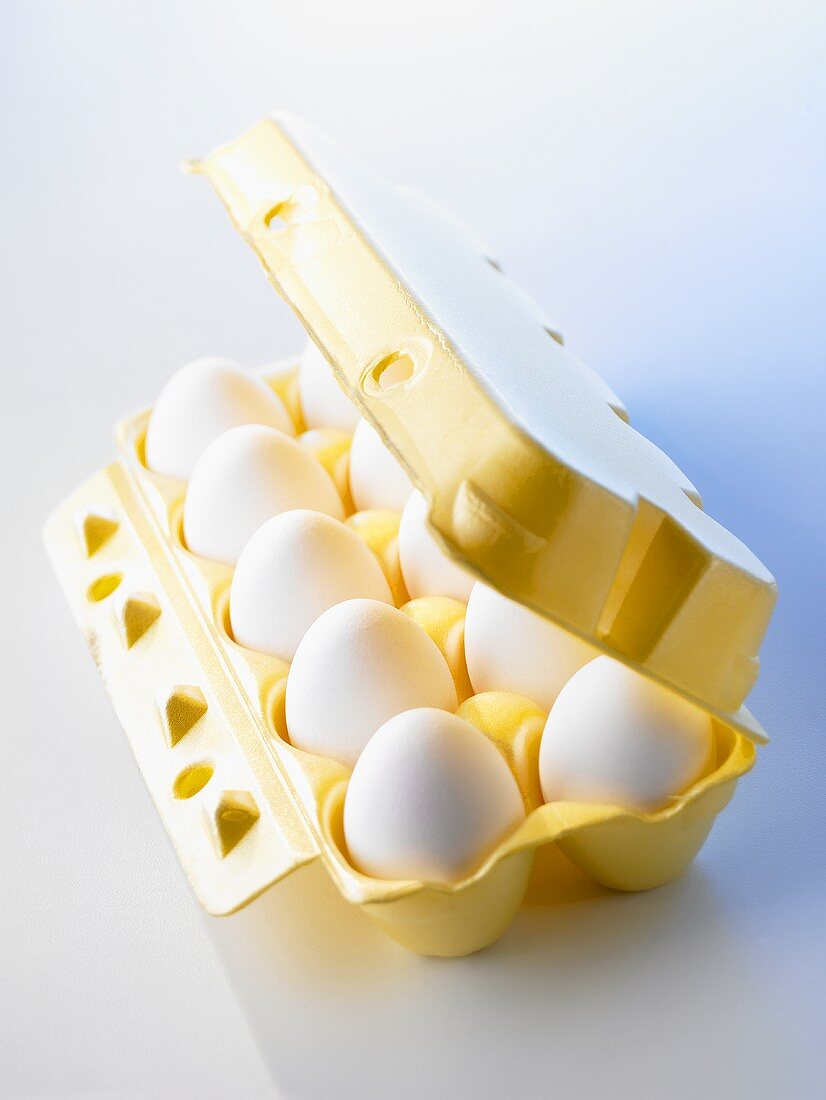 Ten white eggs in a yellow egg box