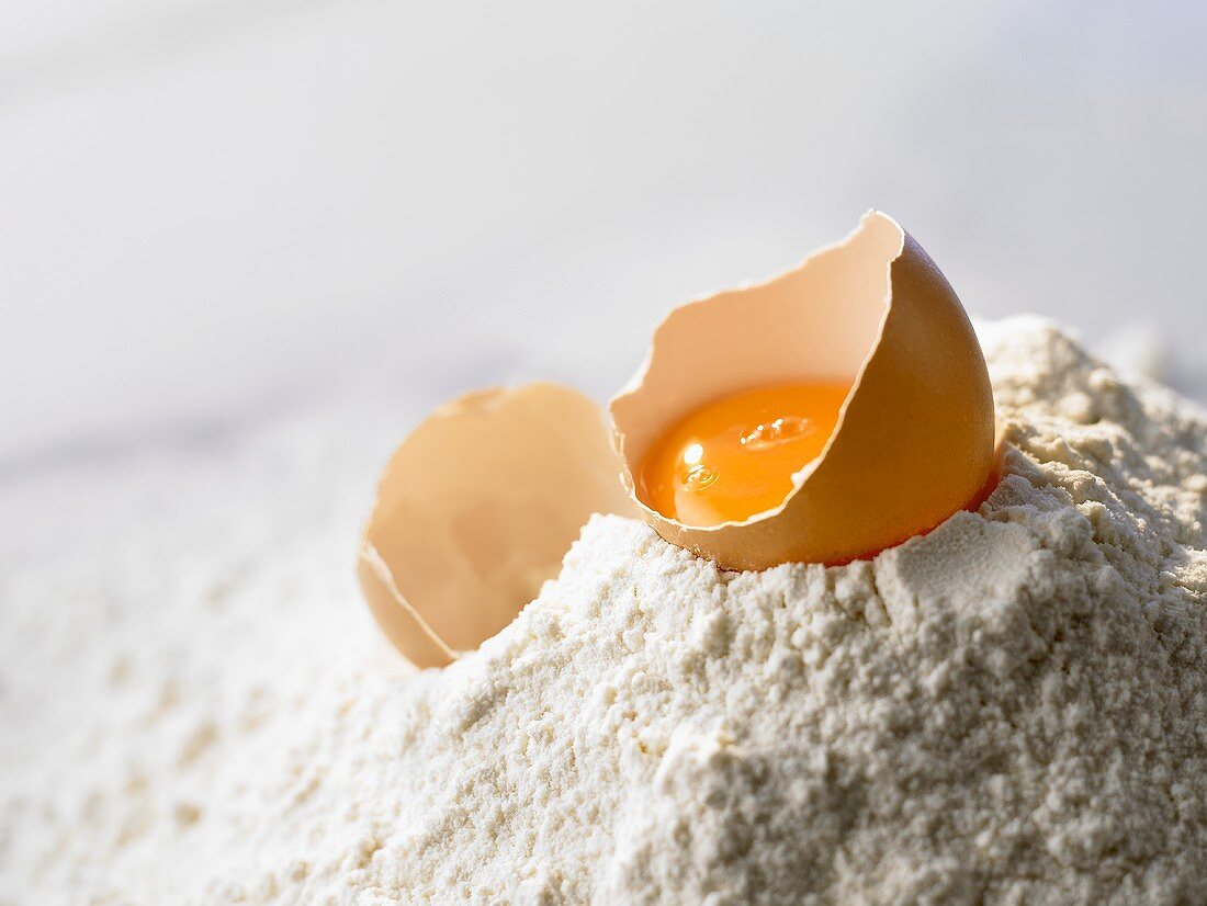 Egg, broken open, lying on flour