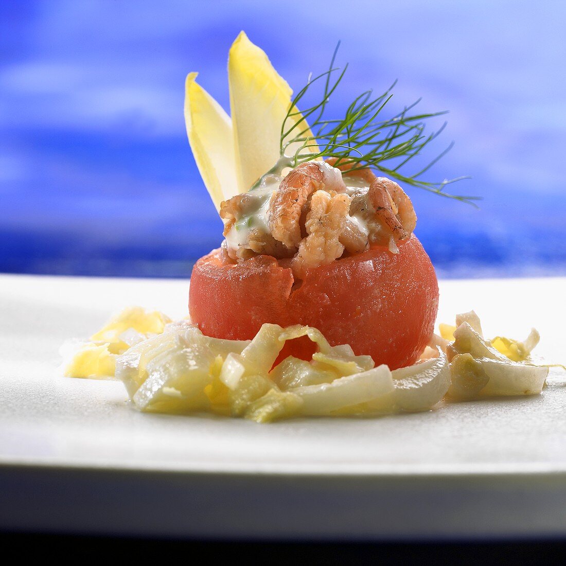 Mit Krabbensalat gefüllte Tomate auf Chicoreesalat