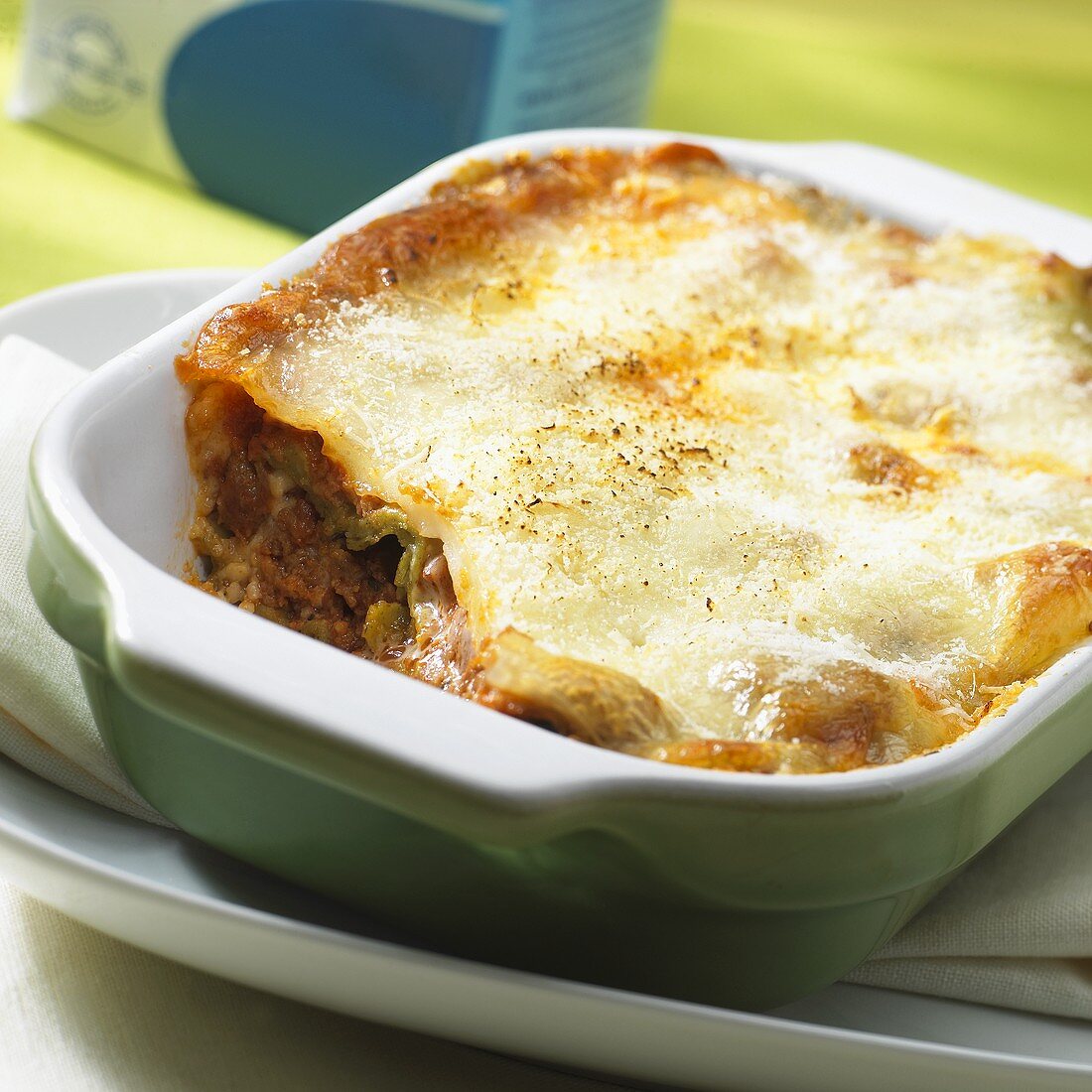 Lasagne, with a piece taken, in a baking dish