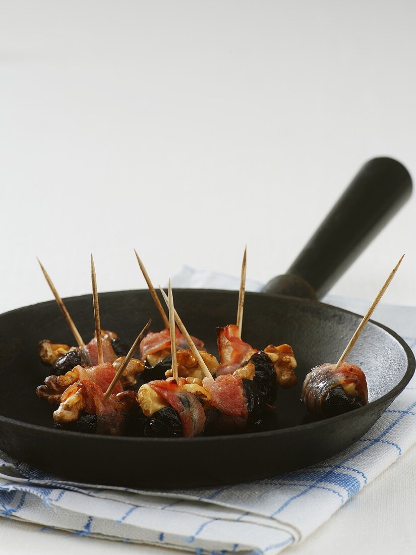 Bacon-wrapped prunes in a frying pan