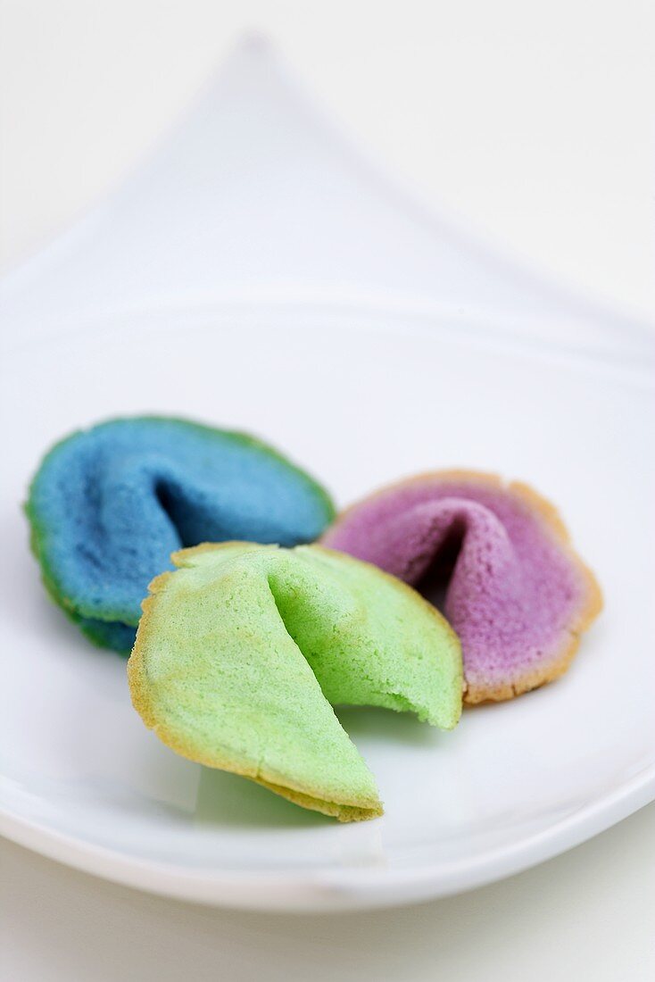 Three different coloured fortune cookies on plate