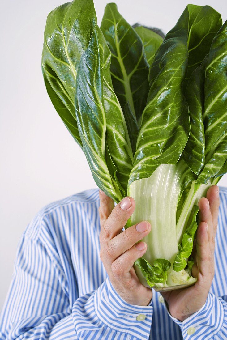 Man holding chard in front of his face