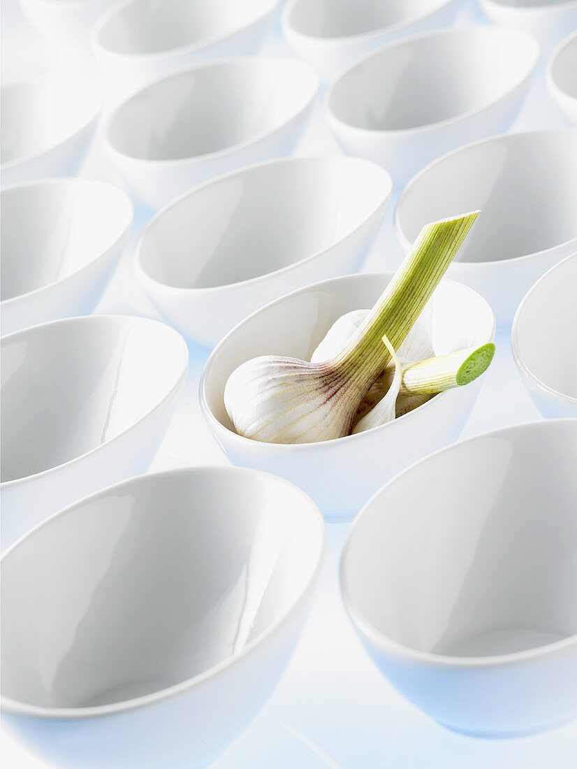 Garlic bulb in a bowl among empty bowls