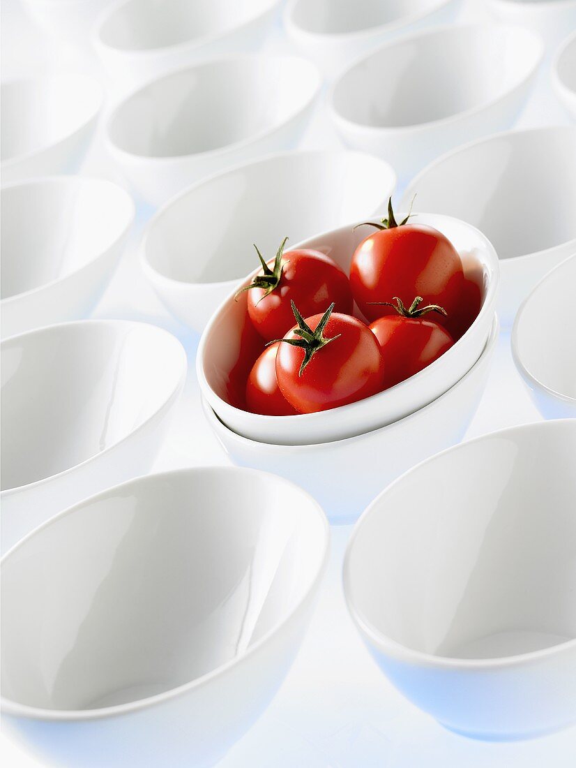 Viele weiße Schalen, eine davon mit Tomaten gefüllt