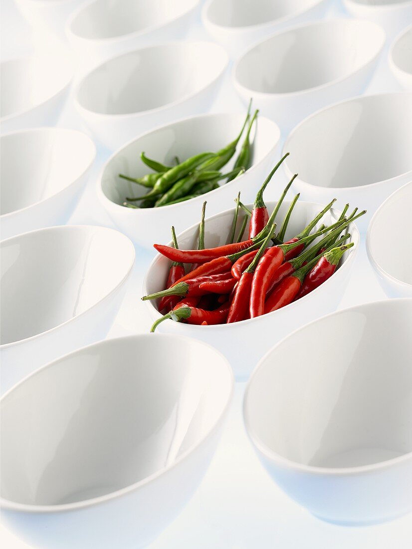 Lots of white bowls, two full of chili peppers