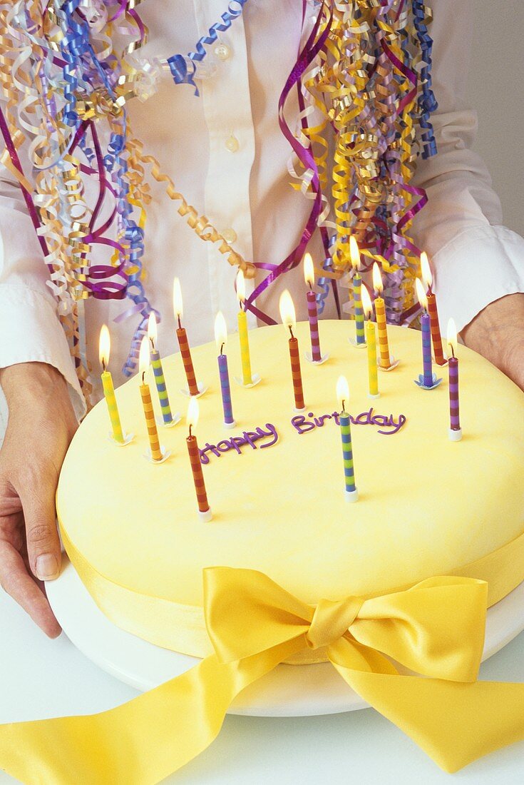 Woman holding birthday cake with burning candles
