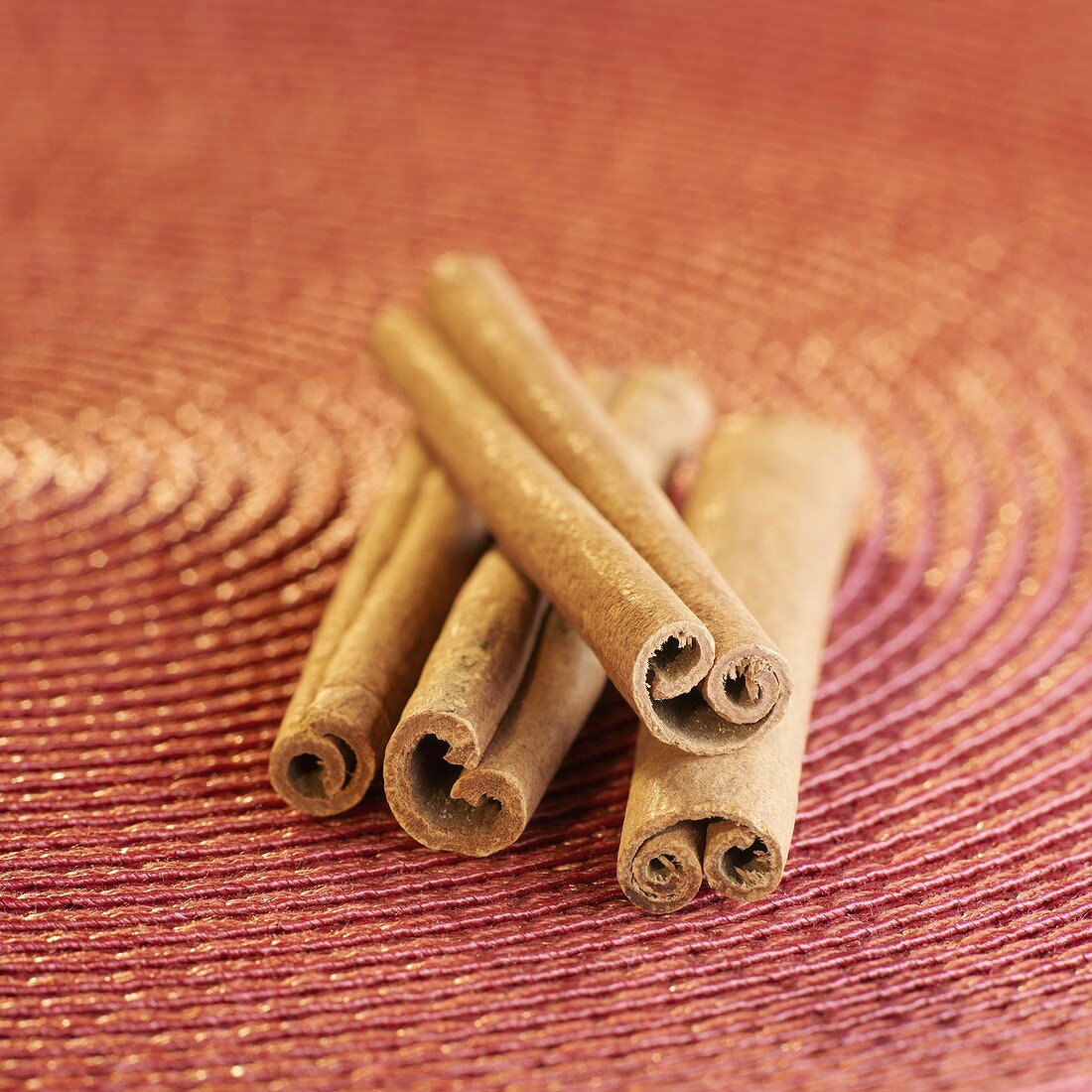 Four cinnamon sticks on red background