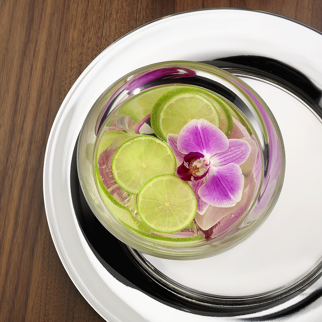 Slices of lime and orchid flower floating in water