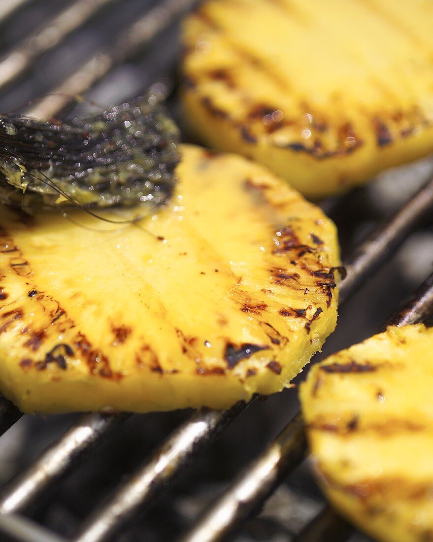 Brushing grilled pineapple with marinade