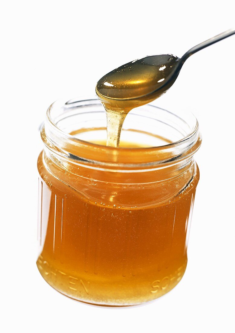 Honey running from spoon into jar