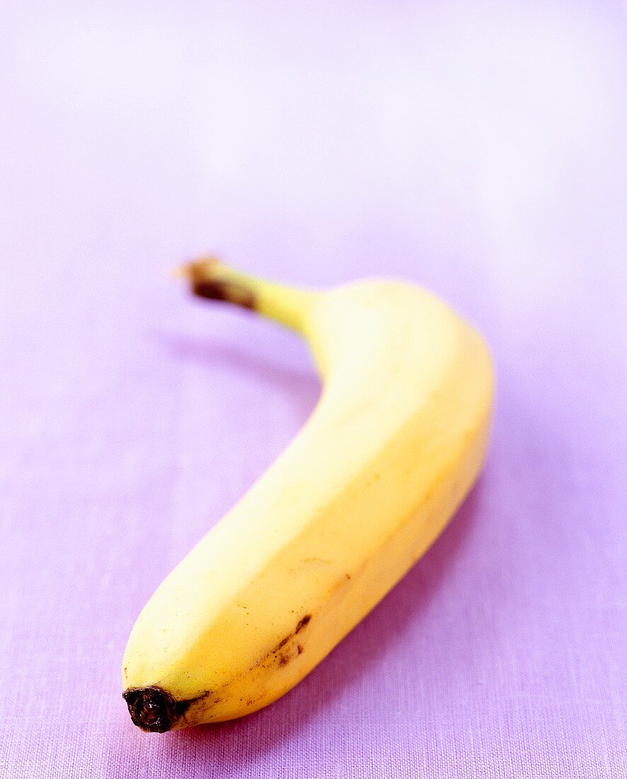 Eine Banane auf violettem Untergrund