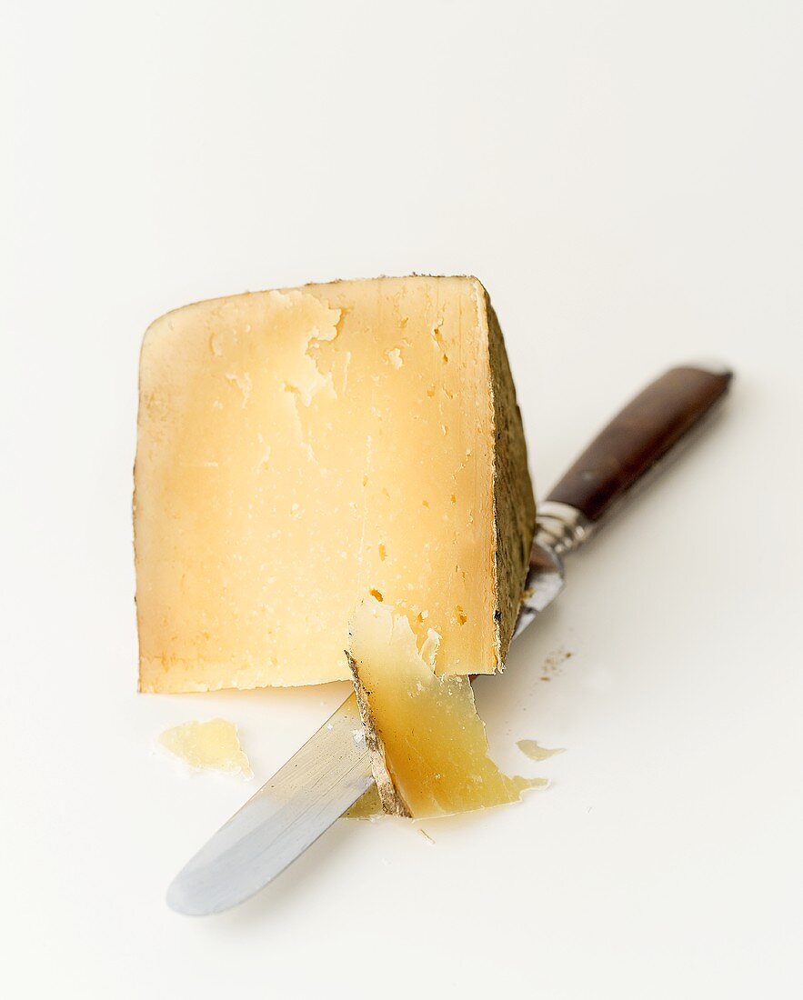 A piece of hard cheese with knife