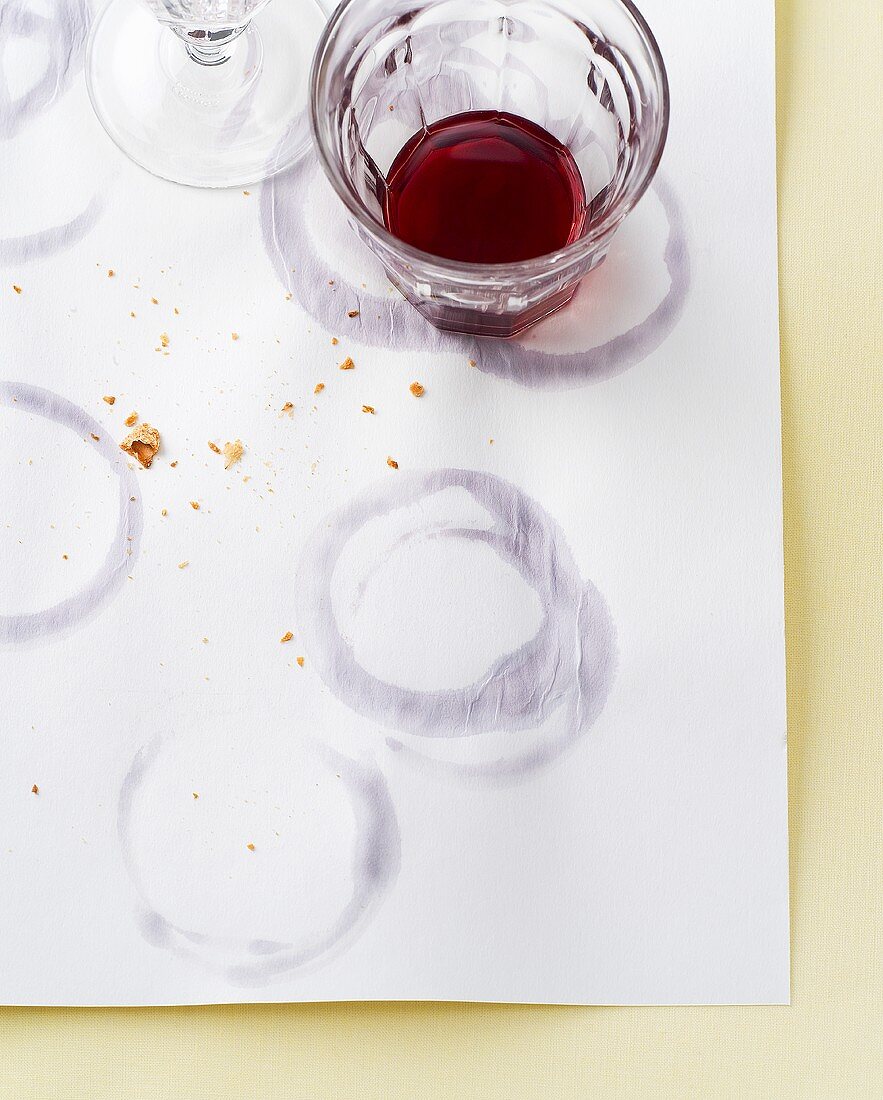 A glass of red wine and glass rings on paper