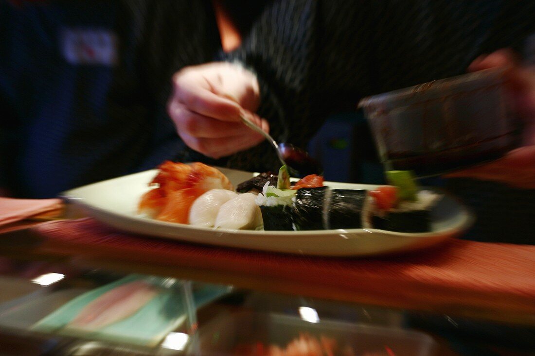 Sushi auf einer Platte mit Sauce beträufeln