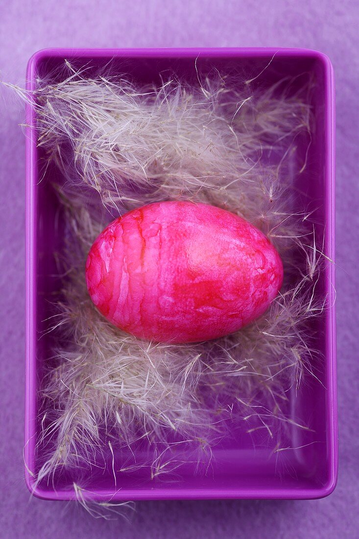 A pink Easter egg in purple bowl